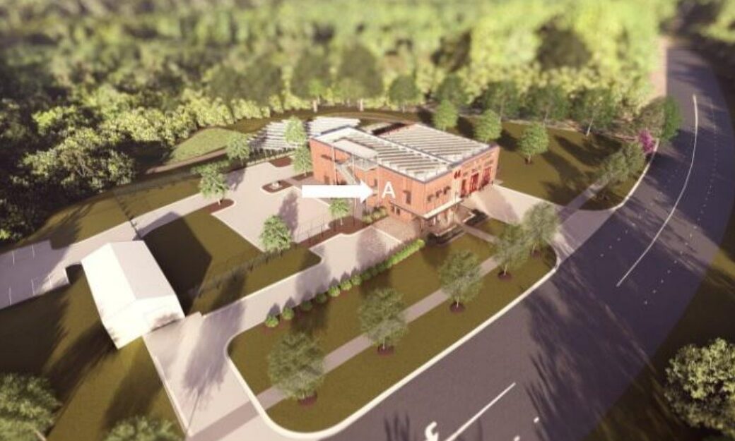 A modern, multi-story brick public safety building. An arrow shows where artwork will be sited.