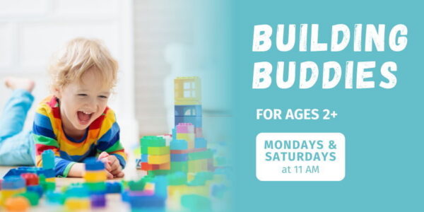 A toddler laughs while playing on the floor with brightly colored blocks.