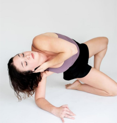 A woman in dancewear moves on a white surface.