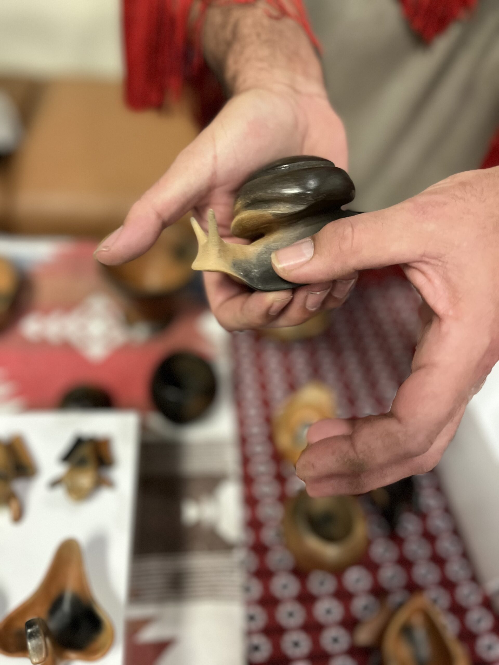 Close-up of hands holding a snail effigy (Catawba pottery)