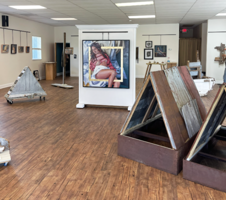 An art gallery with wooden floors and art installed on walls.